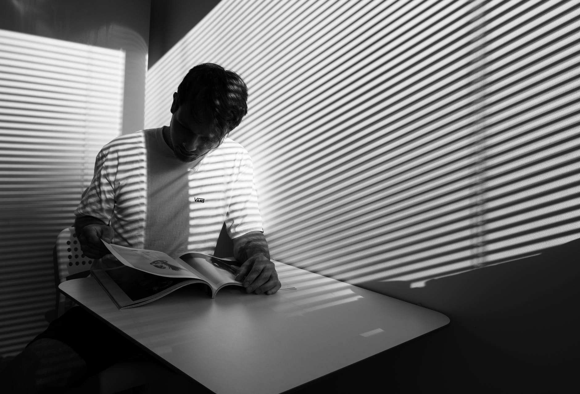 grayscale photography of a man reading book